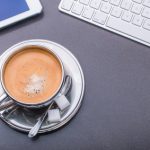 Kaffeetasse umrahmt von Tastatur, Smartphone und Tablet