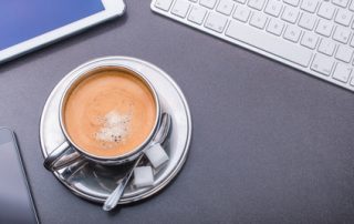 Kaffeetasse umrahmt von Tastatur, Smartphone und Tablet